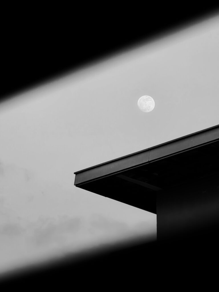 Full moon visible above modern building roof